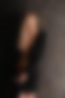 Фото Девушка в расстегнутом черном платье стоит у стены