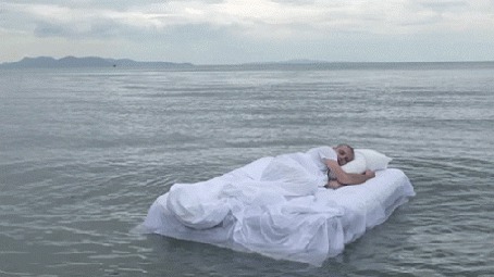 Анимация Человек спит на постели, плавающей по воде