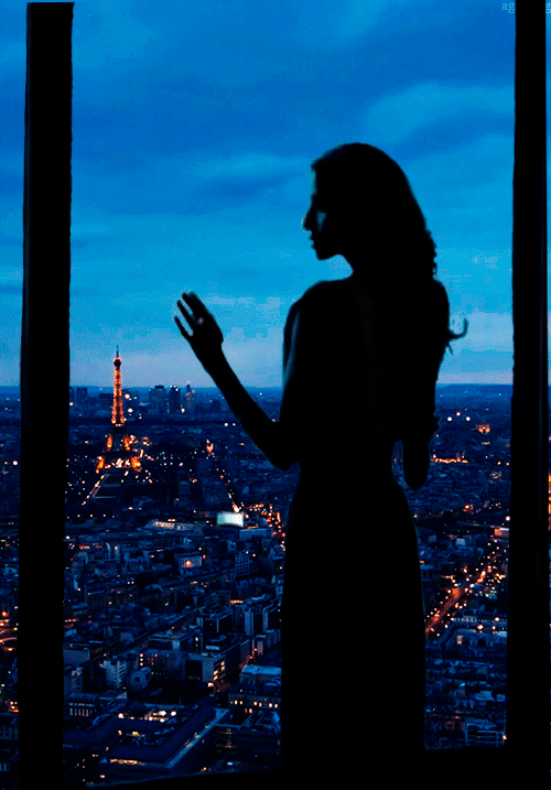 Анимация Девушка в сумерках стоит у окна, и любуется блеском огней вечернего Парижа, задумчиво водя пальцами по стеклу, гифка Девушка в сумерках стоит у окна, и любуется блеском огней вечернего Парижа, задумчиво водя пальцами по стеклу