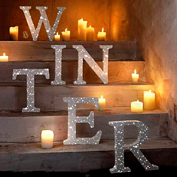 Анимация Переливающиеся буквы слова winter / зима на ступеньках рядом с горящими свечами, гифка Переливающиеся буквы слова winter / зима на ступеньках рядом с горящими свечами