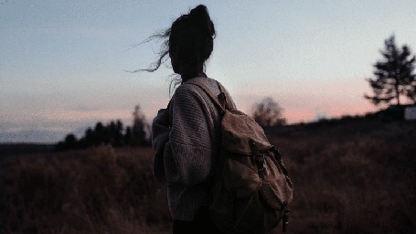 Анимация Девушка с рюкзаком стоит на фоне природы