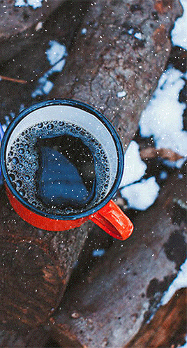 Анимация Красная чашка кофе стоит на бревнах под снегопадом, гифка Красная чашка кофе стоит на бревнах под снегопадом