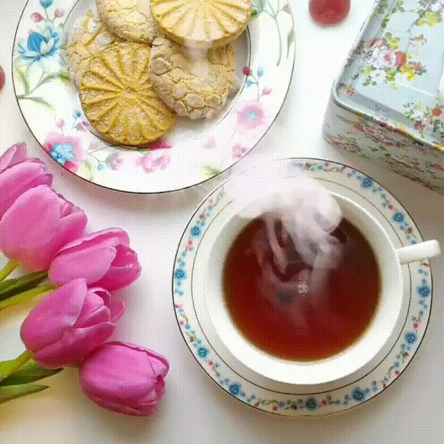 Анимация Чашка горячего чая на блюдце, печенье в тарелке и розовые тюльпаны на столе, гифка Чашка горячего чая на блюдце, печенье в тарелке и розовые тюльпаны на столе