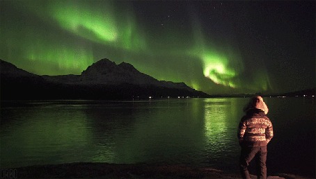 Анимация Девушка смотрит на северное сияние над горами