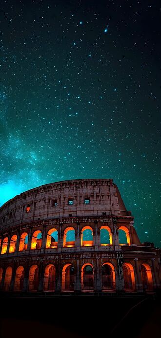 обои на телефон Колизей / Colosseum, Рим / Rome, Италия / Italy, древний амфитеатр освещен оранжевым светом, на фоне звездного неба с бирюзовым оттенком