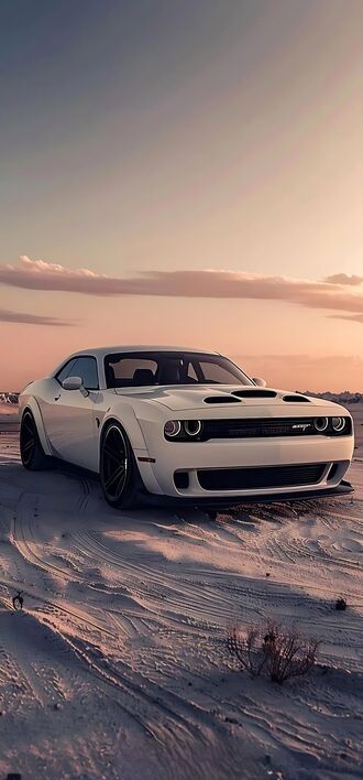 обои на телефон Белый спортивный автомобиль Dodge Challenger на песчаной поверхности, на фоне неба с розовыми и оранжевыми облаками на закате