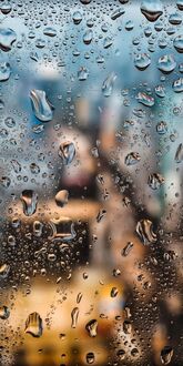 Обои на телефон Множество капель воды на стекле, отражающих свет, на фоне размытых огней и зданий города